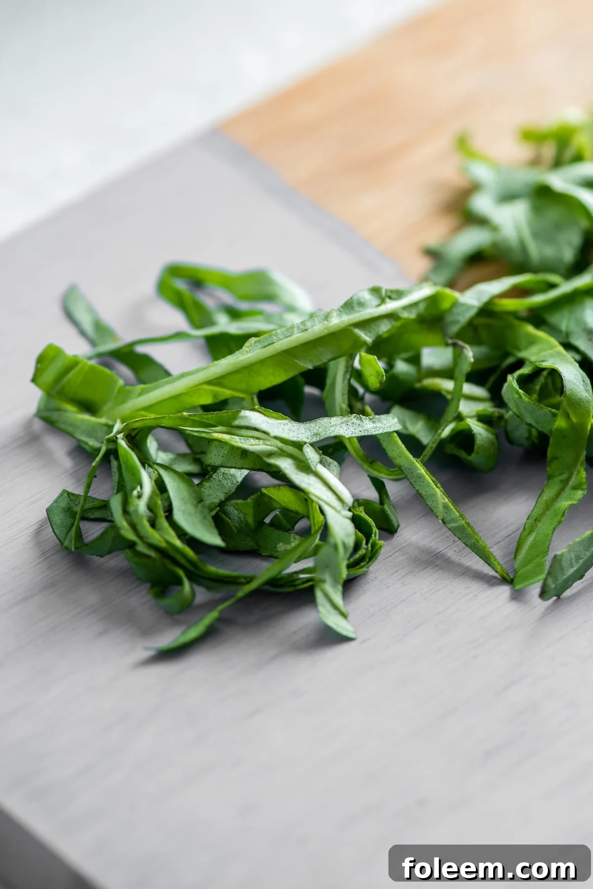 Fresh chiffonaded basil leaves on cutting board.