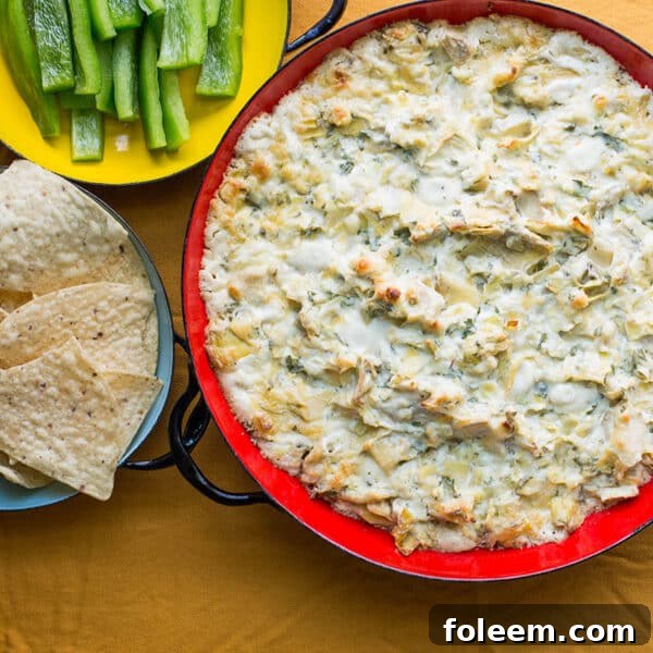 Red bowl of Spicy Cheesy Artichoke Dip.