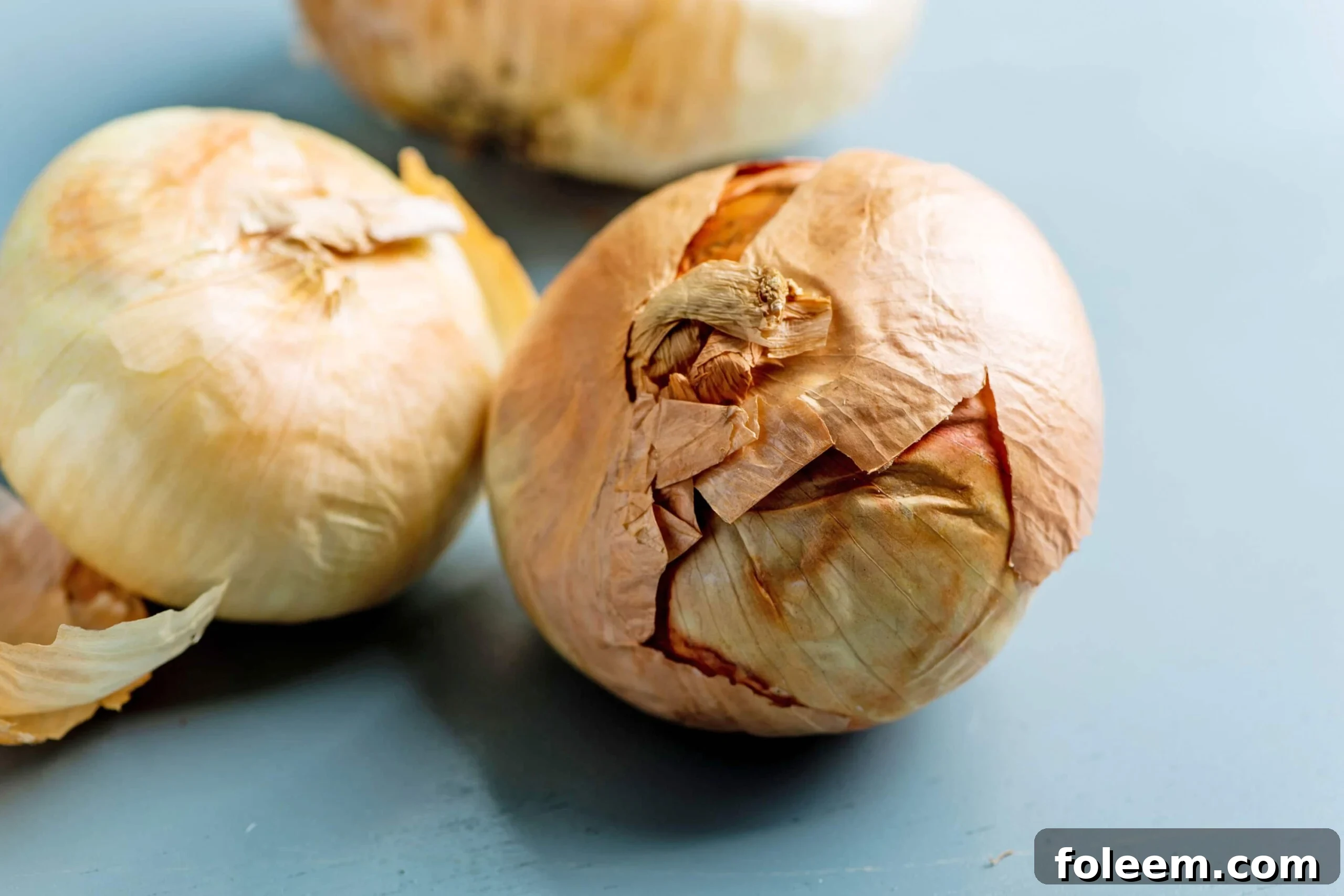 Golden Vidalia Onions sitting on a blue table.