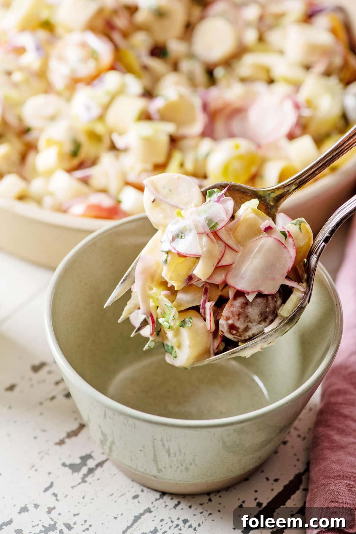 Scooping a portion of Hearts of Palm Salad with spoon and fork in a bowl.