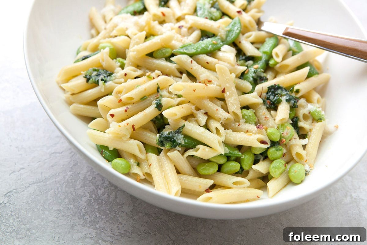 Pasta with Ramps, Edamame, and Sugar Snap Peas in a Light Parmesan Cream Sauce in white bowl.