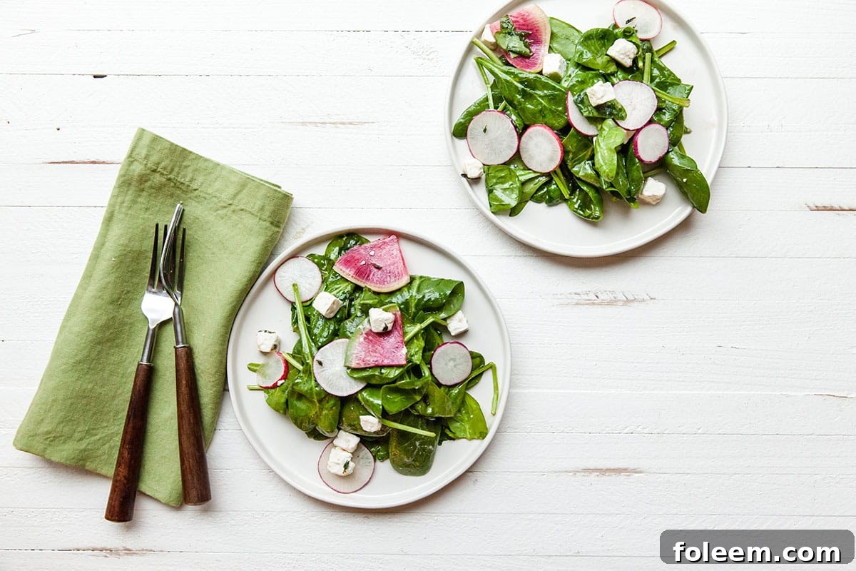 Spinach and Radish Salad with Feta on white plates.
