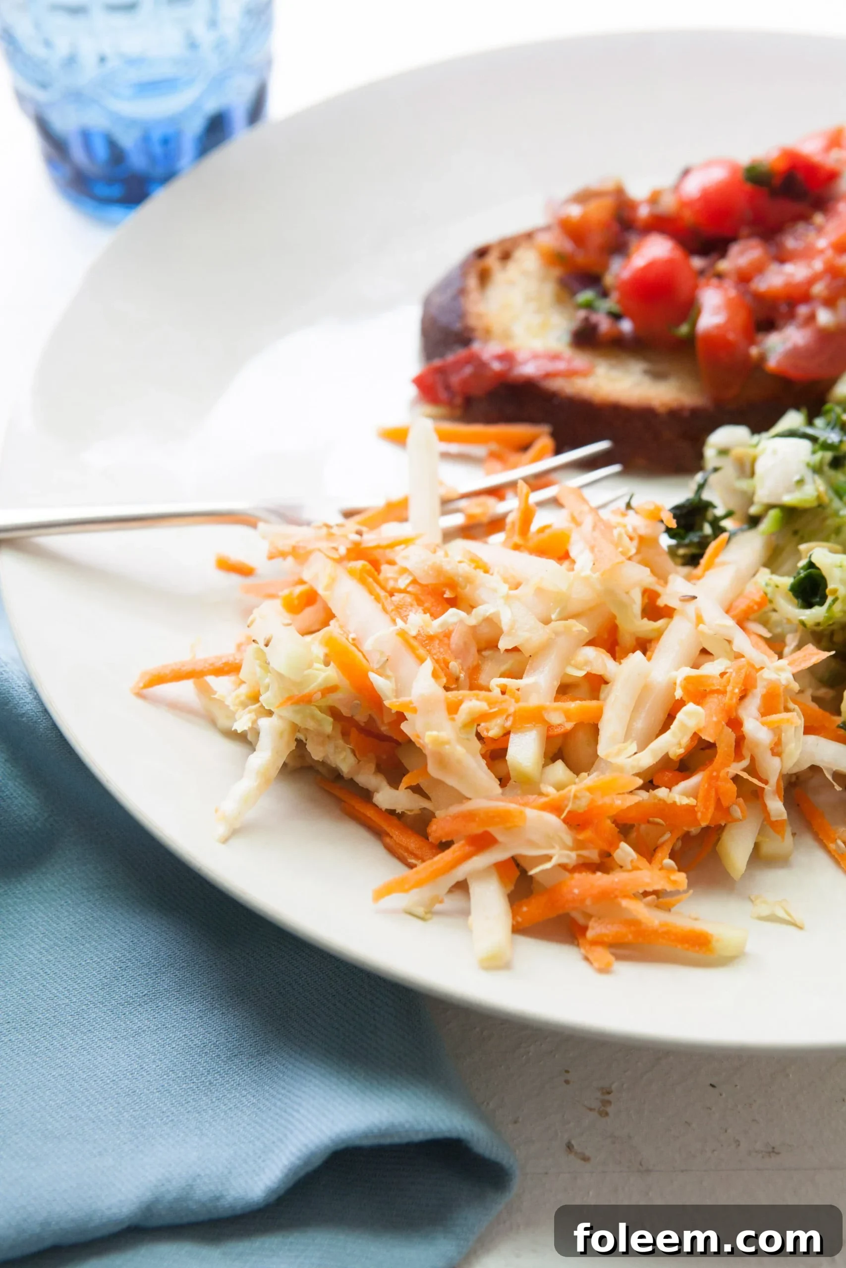Carrot, Cabbage and Kohlrabi Slaw with Miso Dressing on white plate with fork.