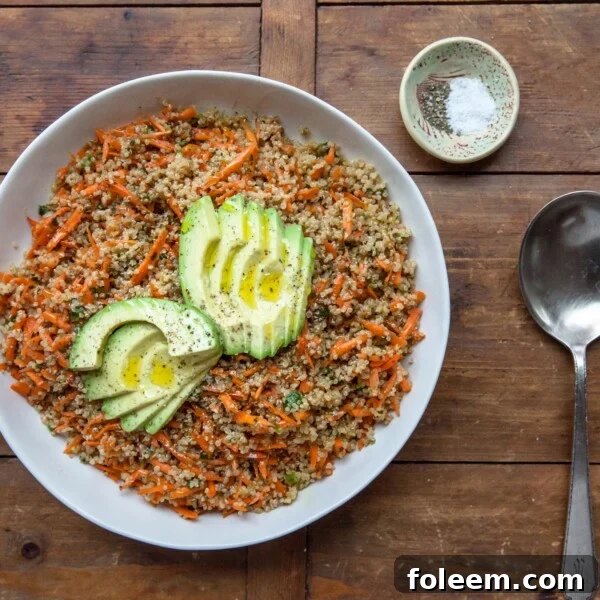 Sesame-Honey Quinoa and Carrot Salad in white bowl, topped with Sliced Avocado.