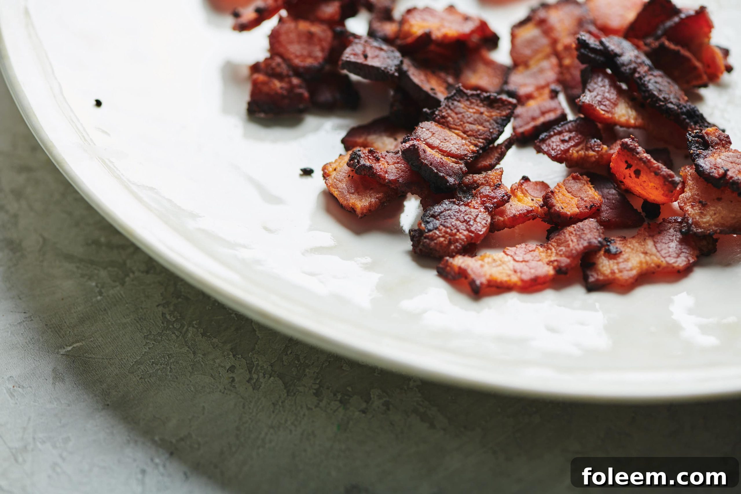Cooked Bacon Lardons on a white plate.
