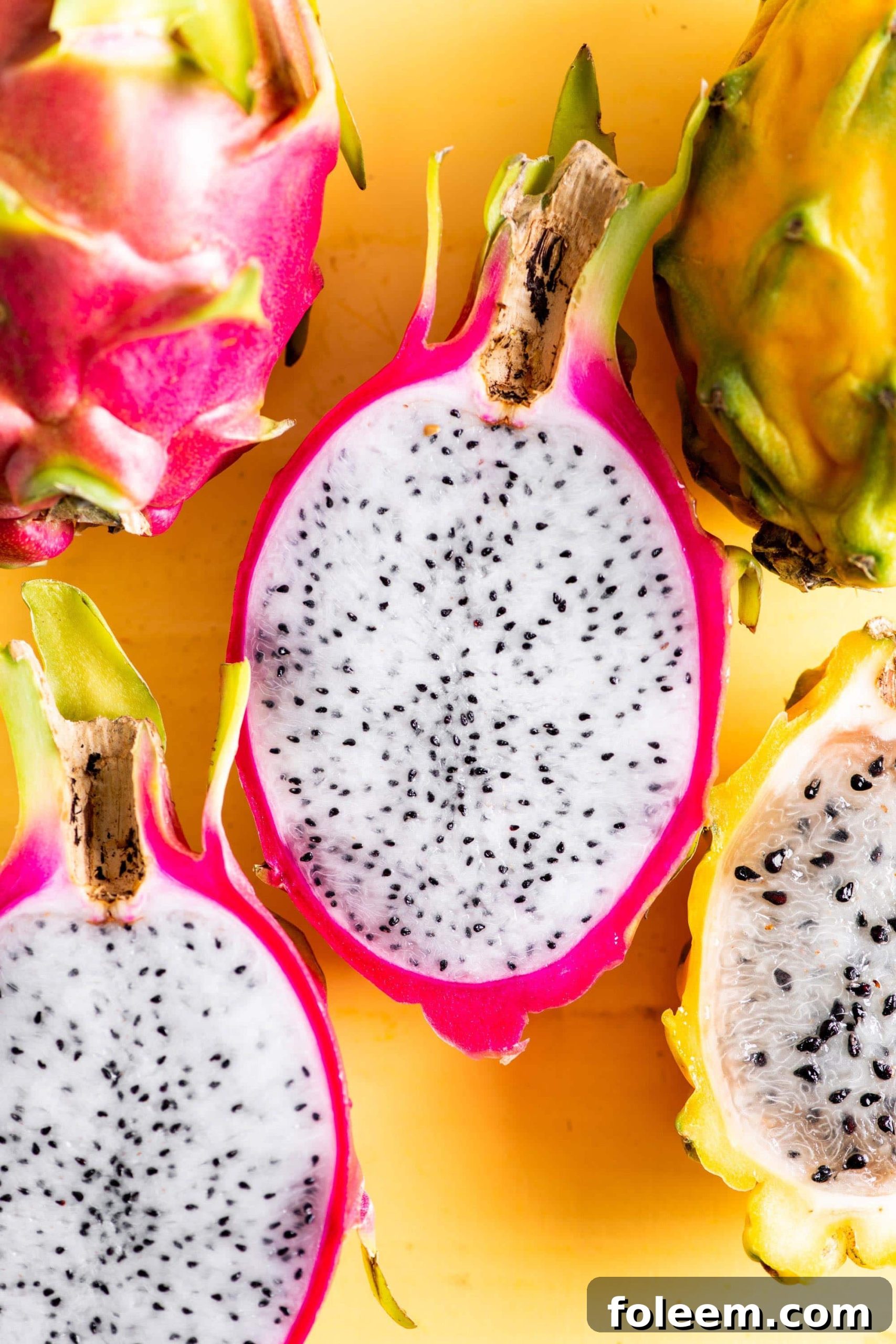 Pink dragon fruit sliced in half to show white interior with black seeds.