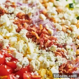 Late Summer Cobb Salad topped with bacon, red onion, crumbled cheese, and other toppings.