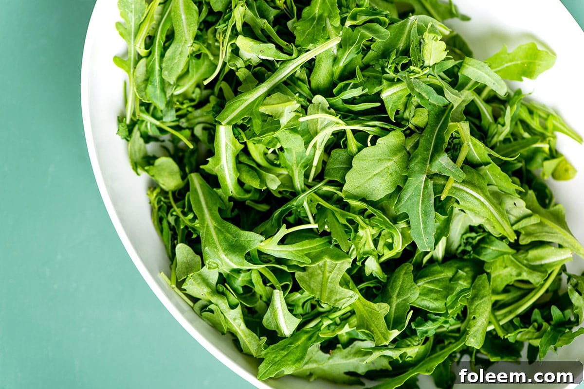 White bowl full of fresh arugula leaves.