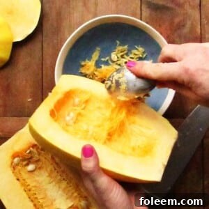 Woman scooping seeds out of a halved spaghetti squash.