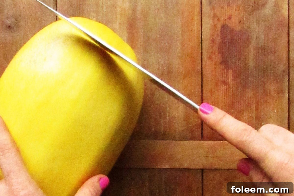 Woman cutting the end off of a spaghetti squash.
