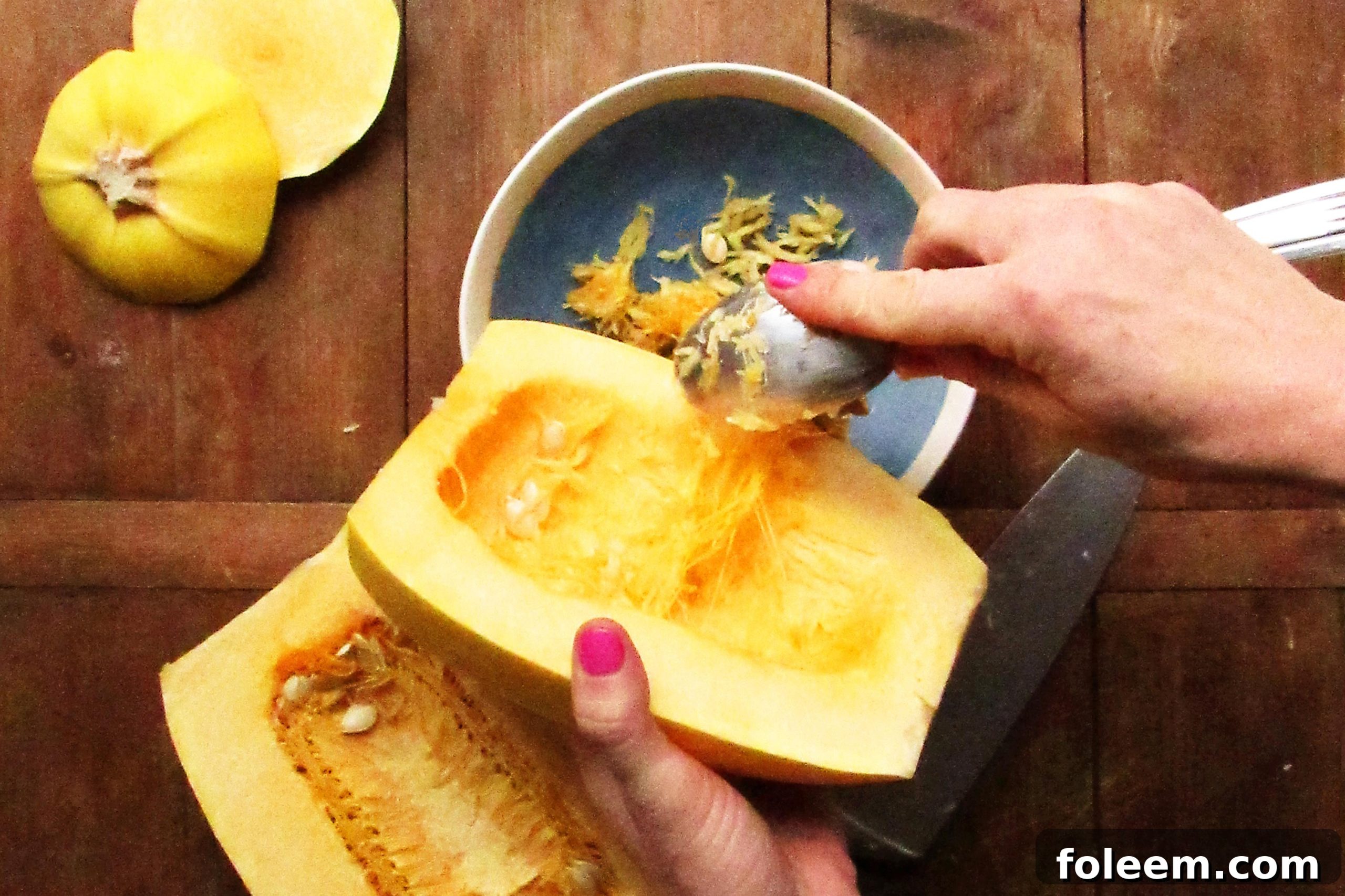 Woman scooping seeds out of a halved spaghetti squash.