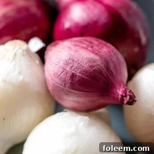 Purple and white pearl onions stacked on blue table.