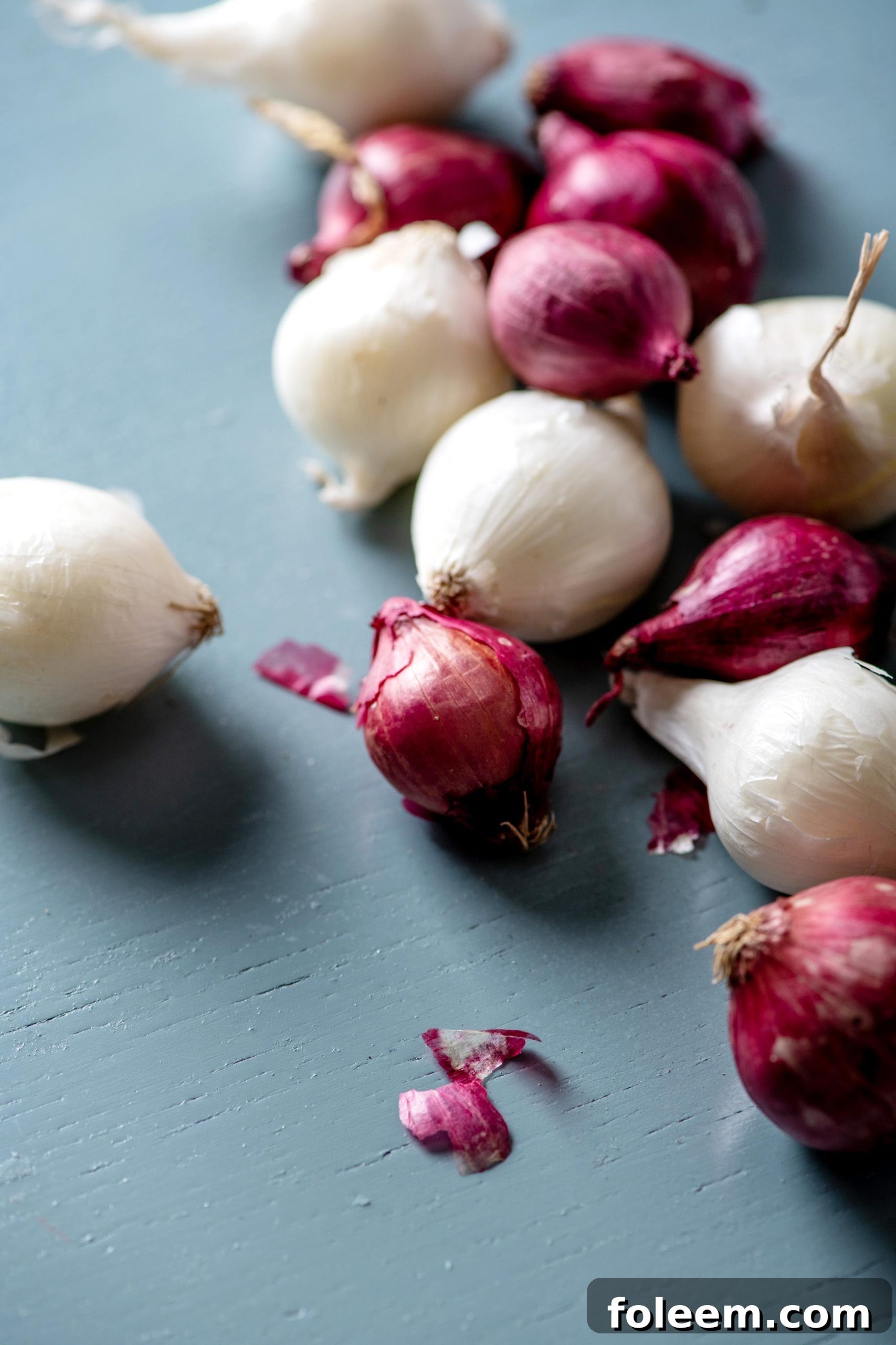 Red and white pearl onions on a blue surface.