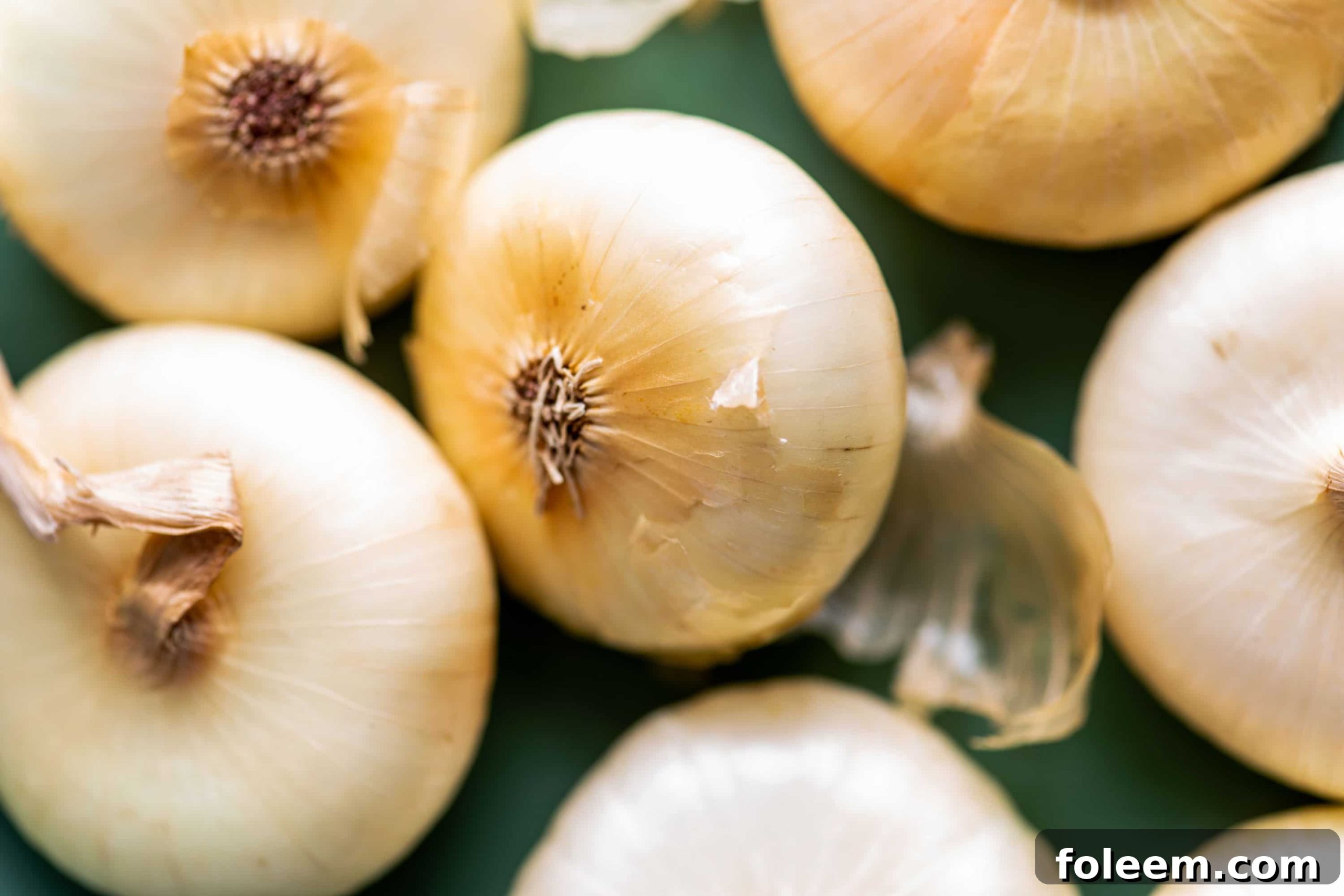 Cipollini Onions on a green board.