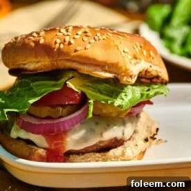 Grilled turkey burger with toppings and bun on white plate.