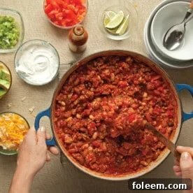 Serving turkey chili from pot next to chili toppings.
