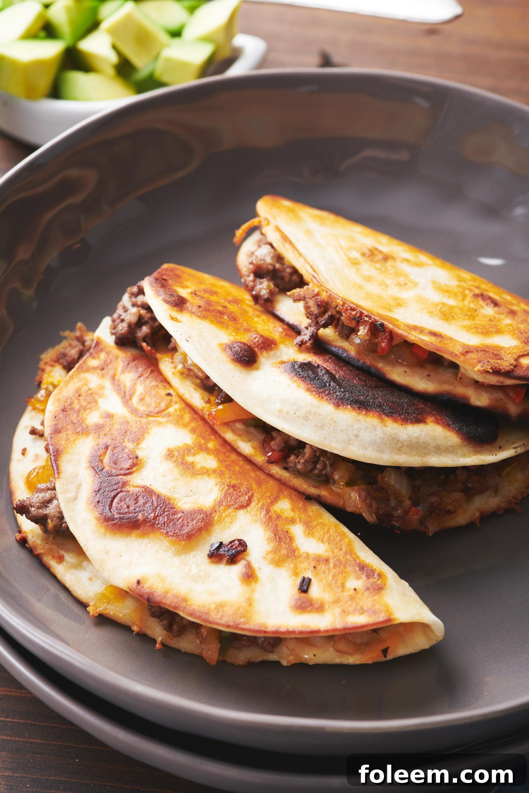 Cheesy Ground Beef and Vegetable Quesadillas stacked on grey plate.