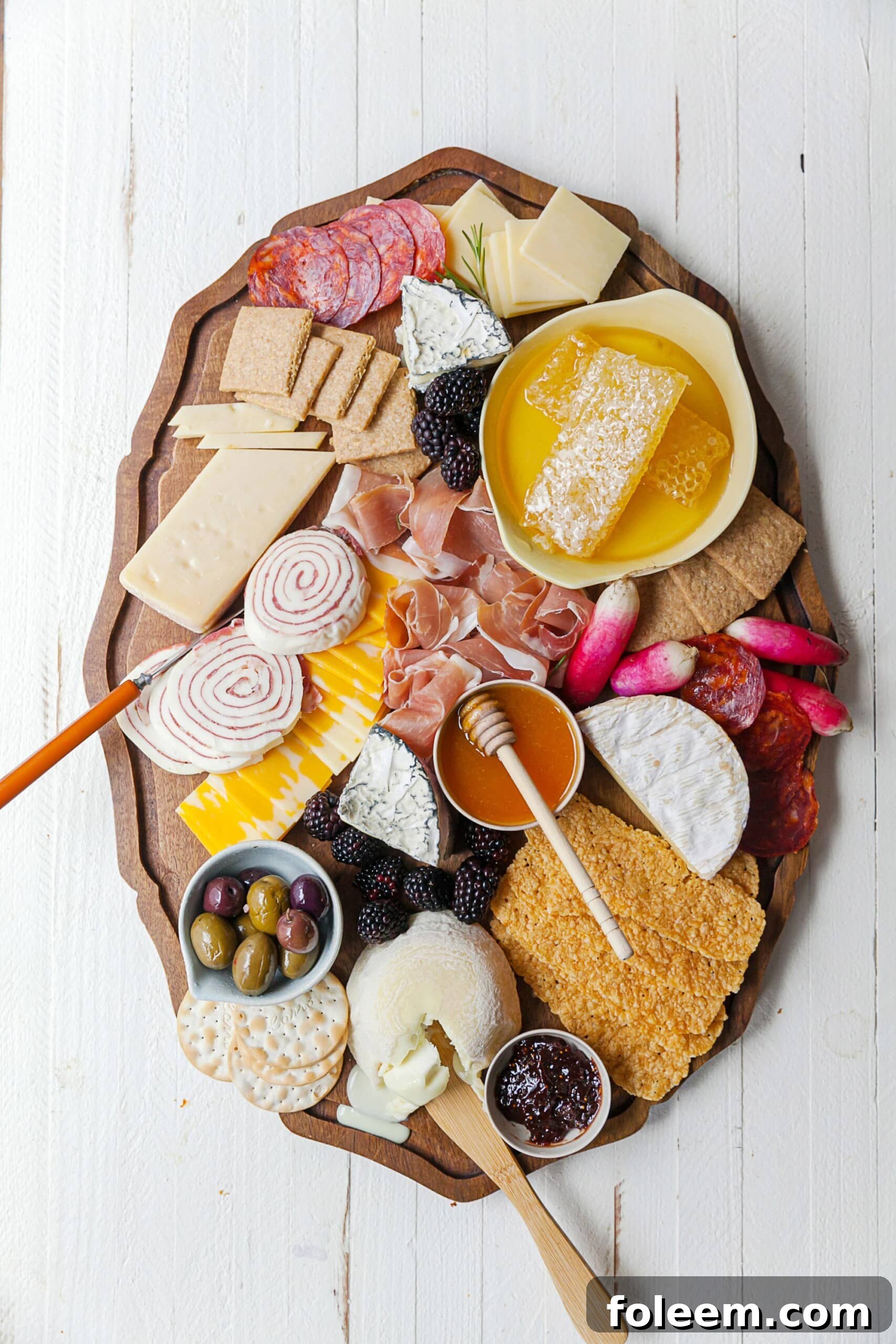 Graze Board with honey, meat, cheese, olives, fruit, crackers, and other foods.