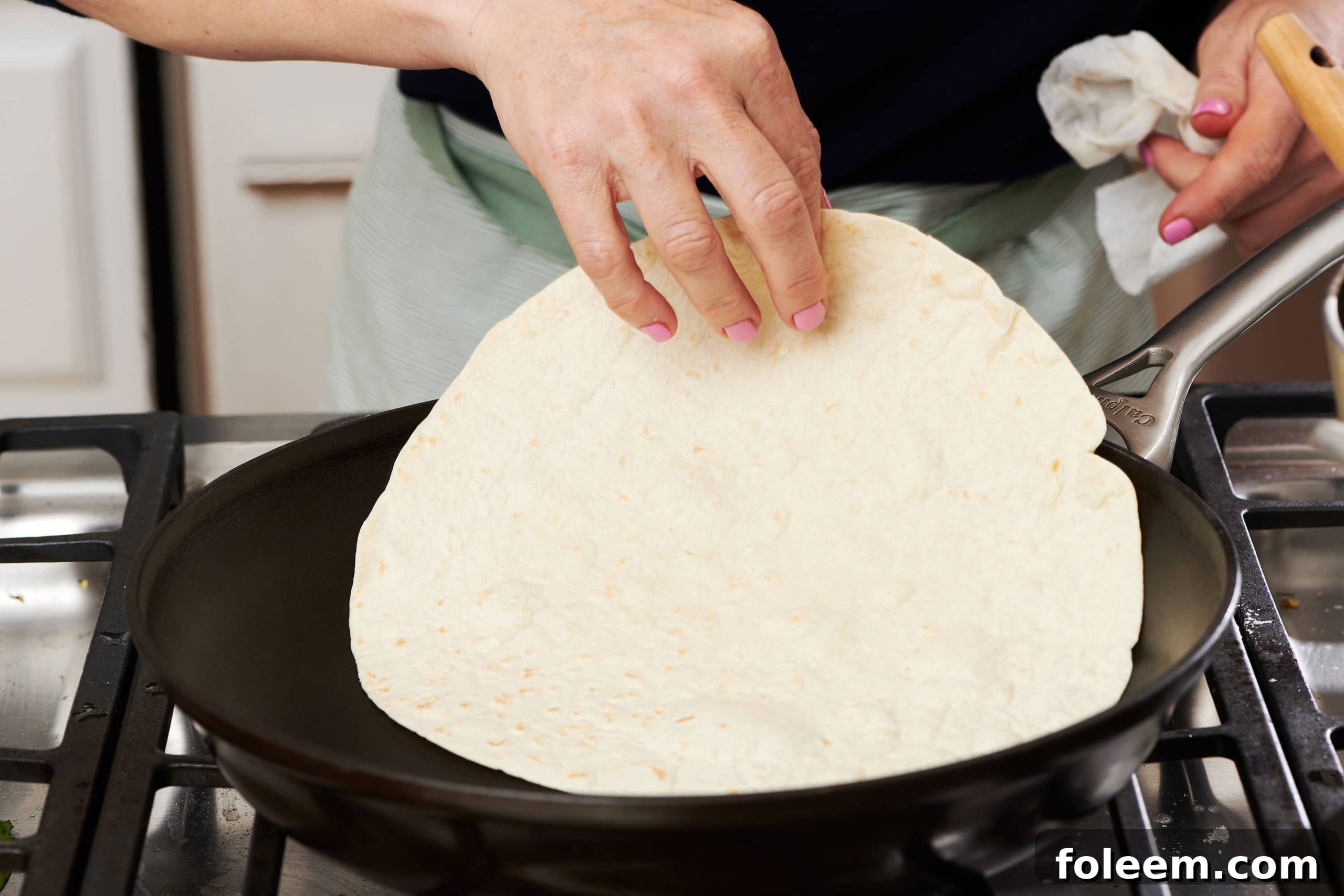 Placing tortilla in hot pan.