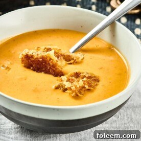Pumpkin Curry Soup in white and black bowl on table.