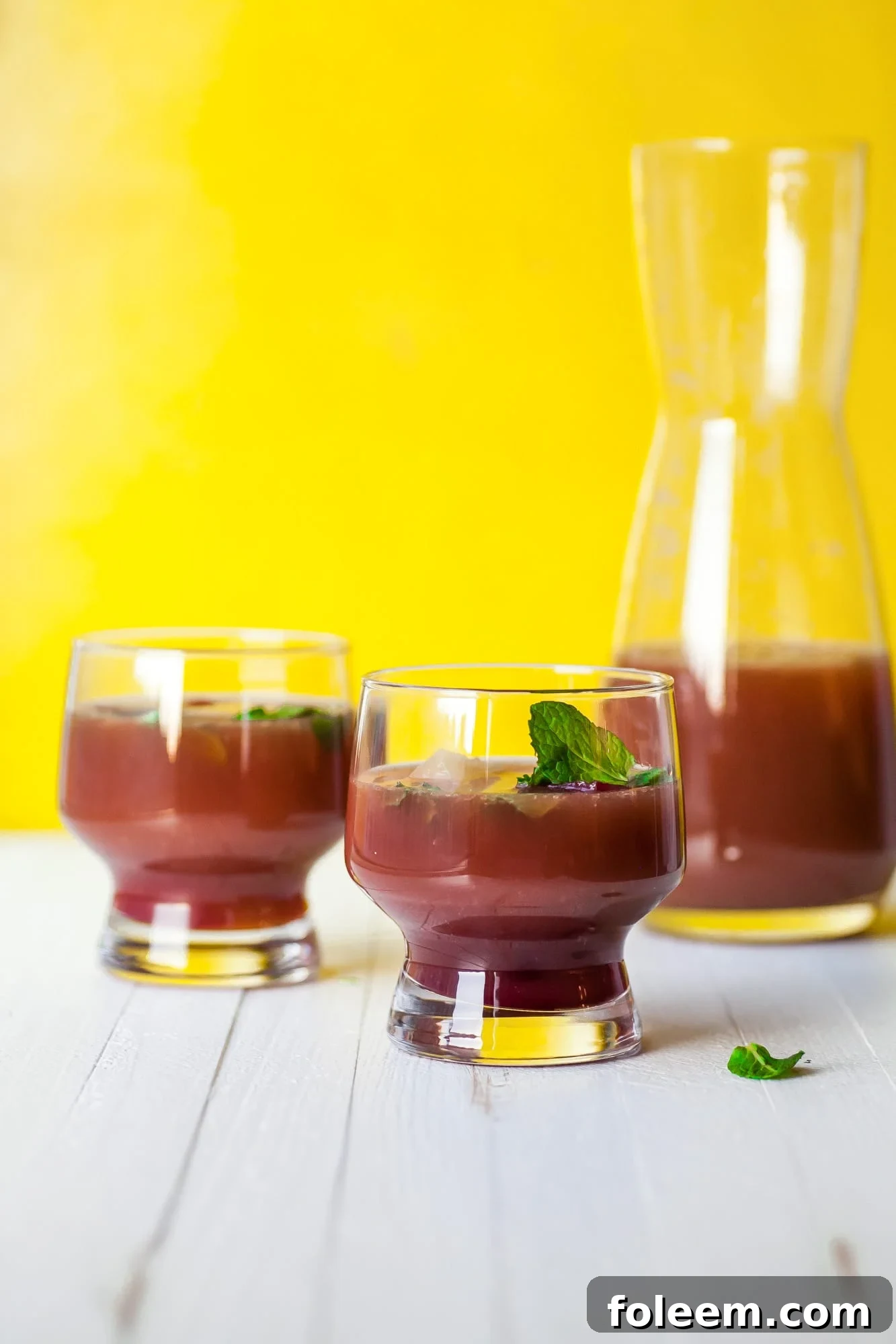 Two glasses of Pomegranate Orange Mocktail with Mint.