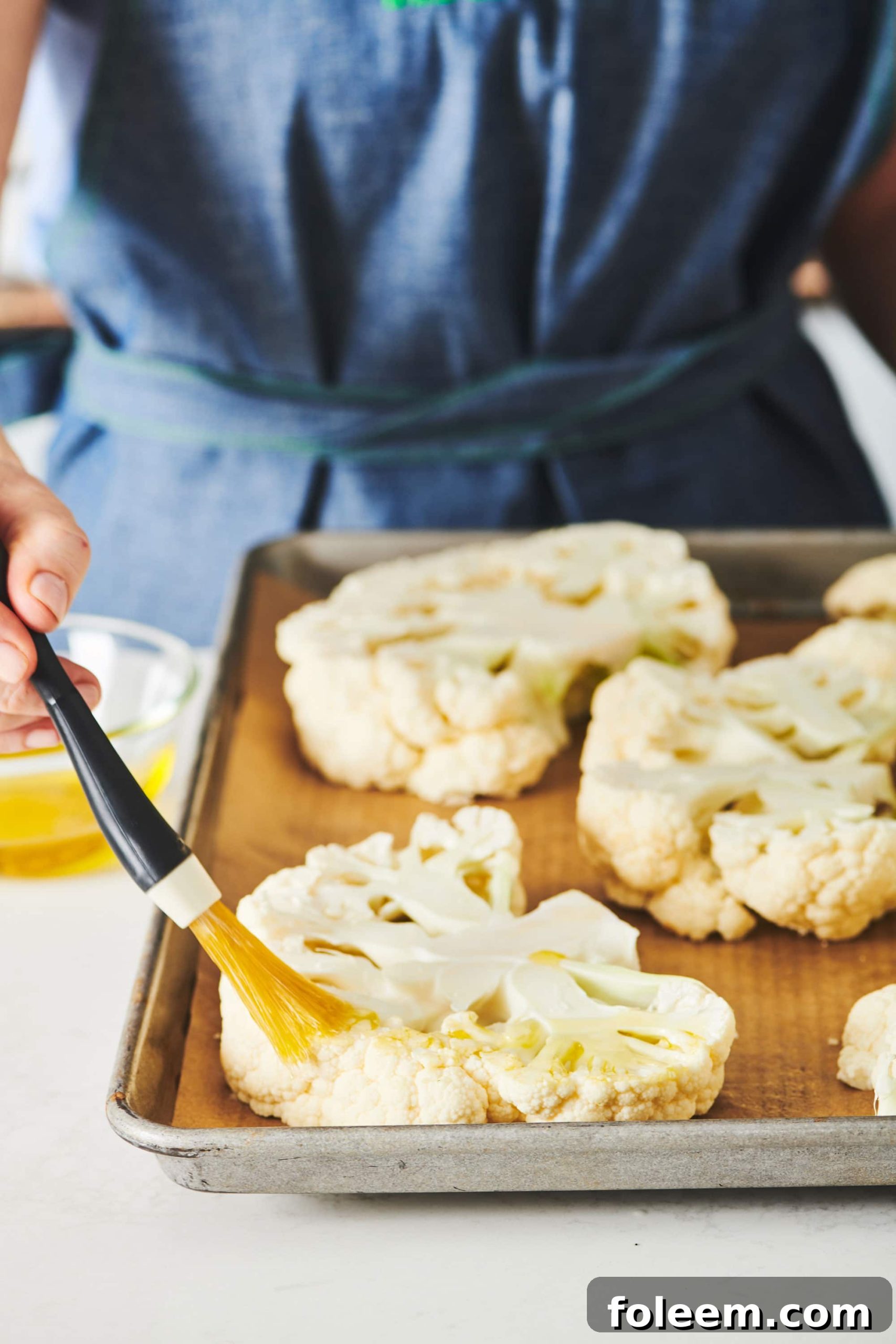 Woman spreading butter on cauliflower slices.