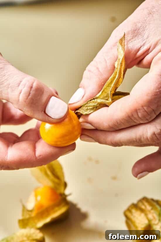Woman removing the husk from a golden berry.