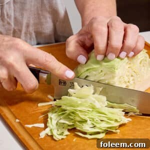Woman slicing cabbage on cutting board.