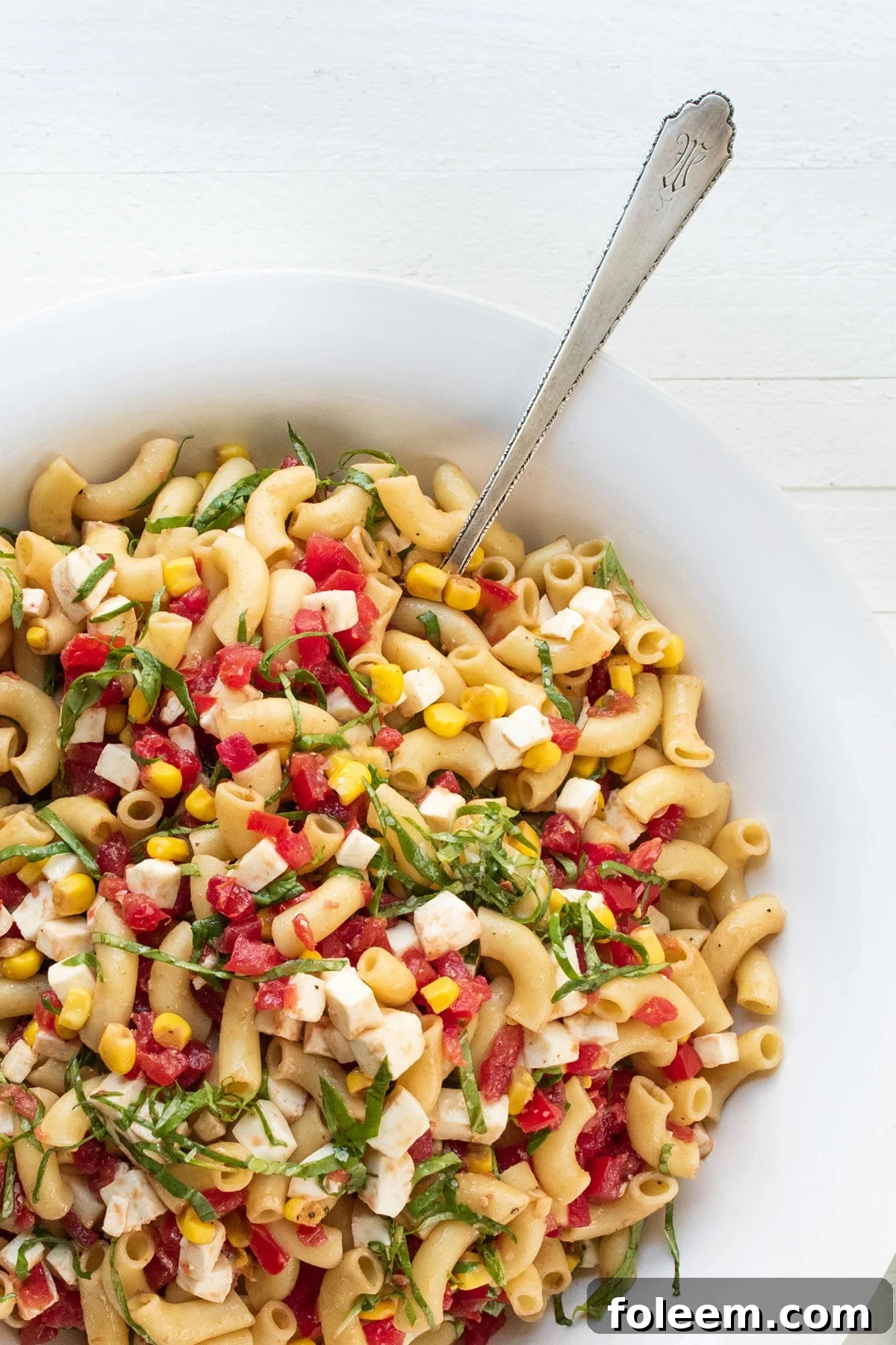 Simplest Tomato, Corn, Basil and Mozzarella Pasta Salad in a white bowl.