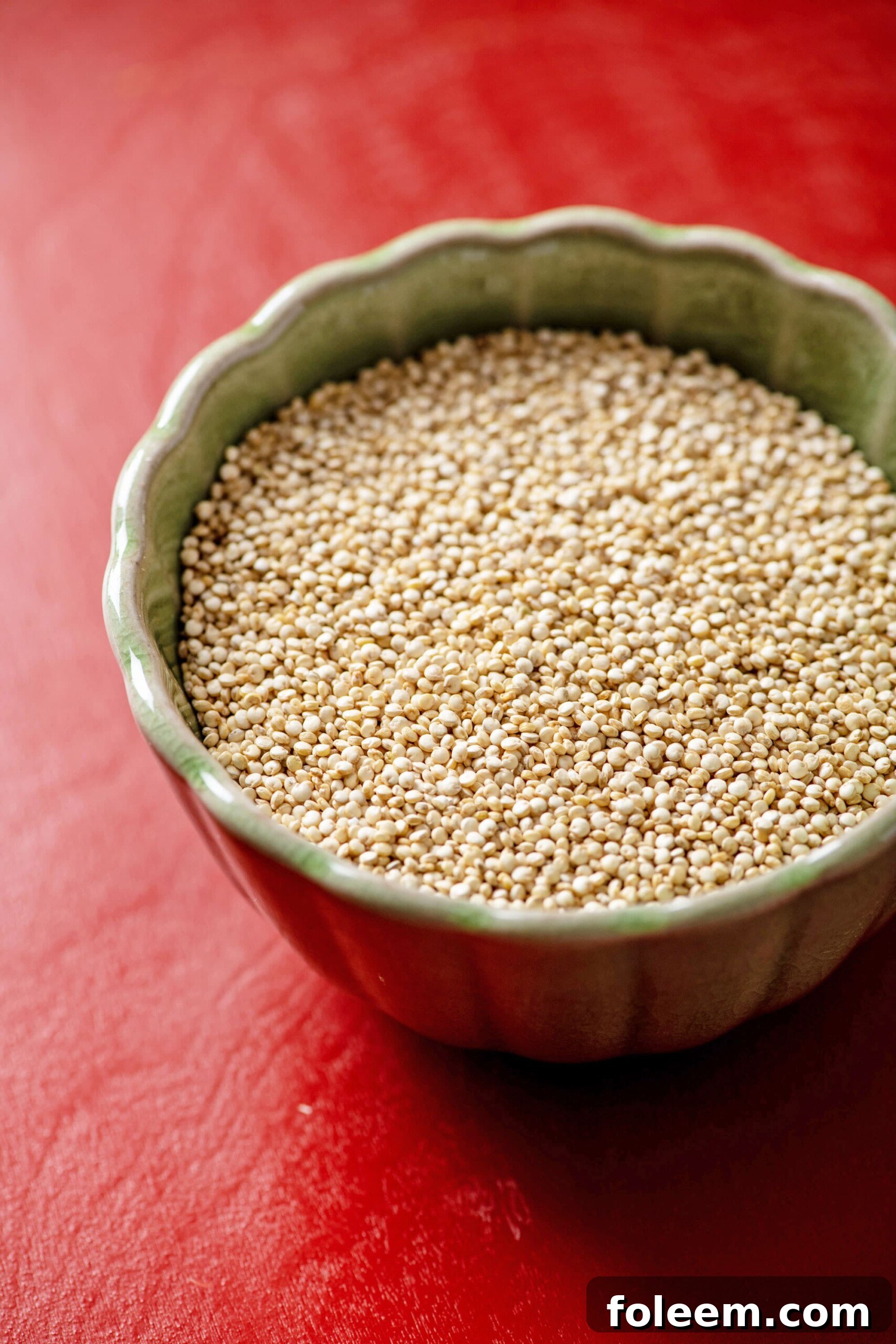 Small bowl of Quinoa on a red table.
