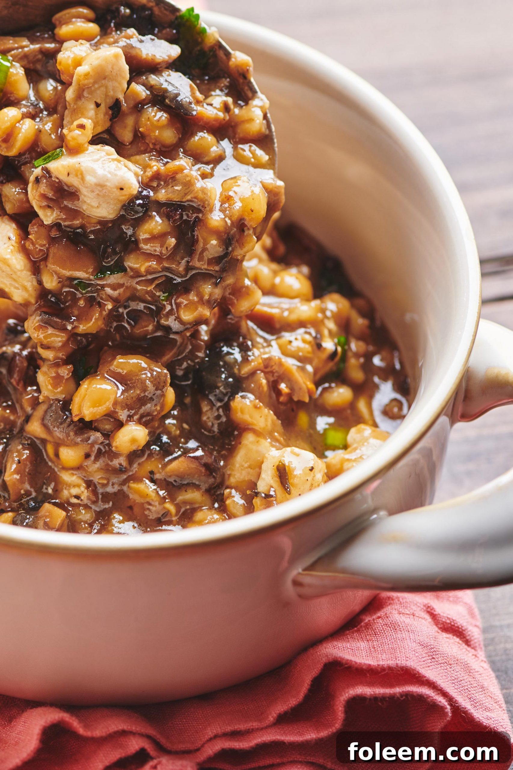 Scooping Chicken, Barley and Shiitake Mushroom Soup into white crock.