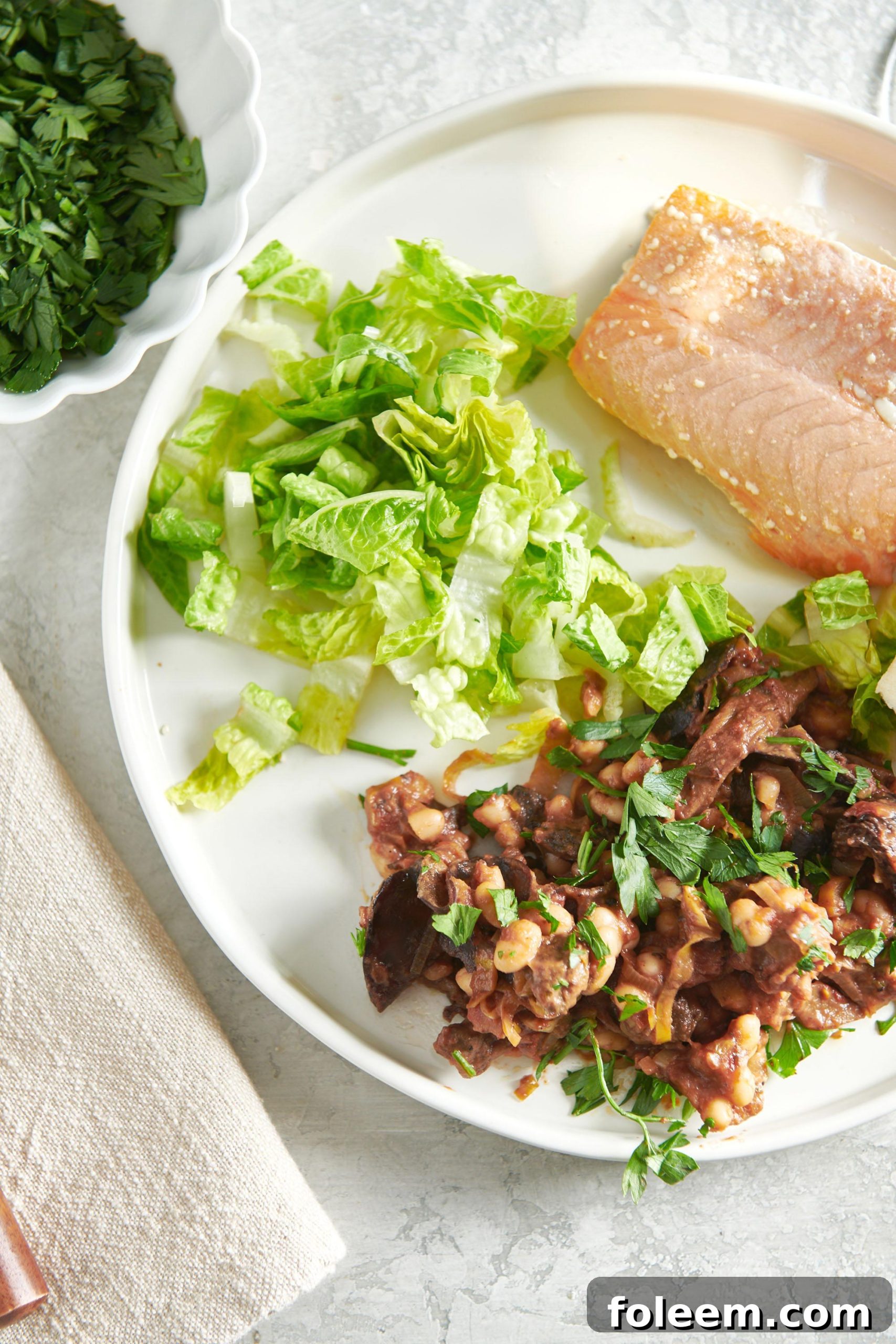 Mushroom, Tomato and White Bean Ragout on white plate with salmon and lettuce.