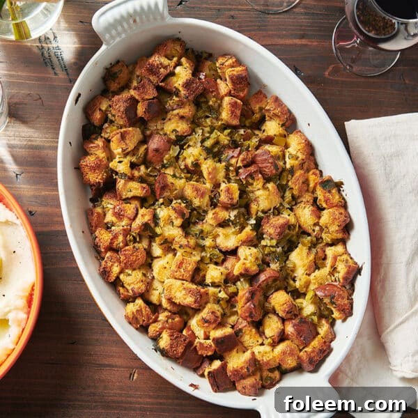Classic stuffing on Thanksgiving dinner table with bowls of mashed potatoes.