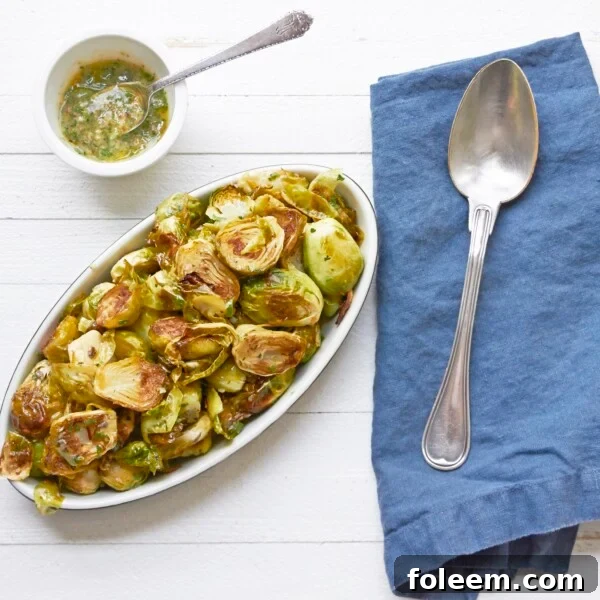 Warm Brussels Sprouts Salad with Anchovy Vinaigrette on platter with napkin and spoon.