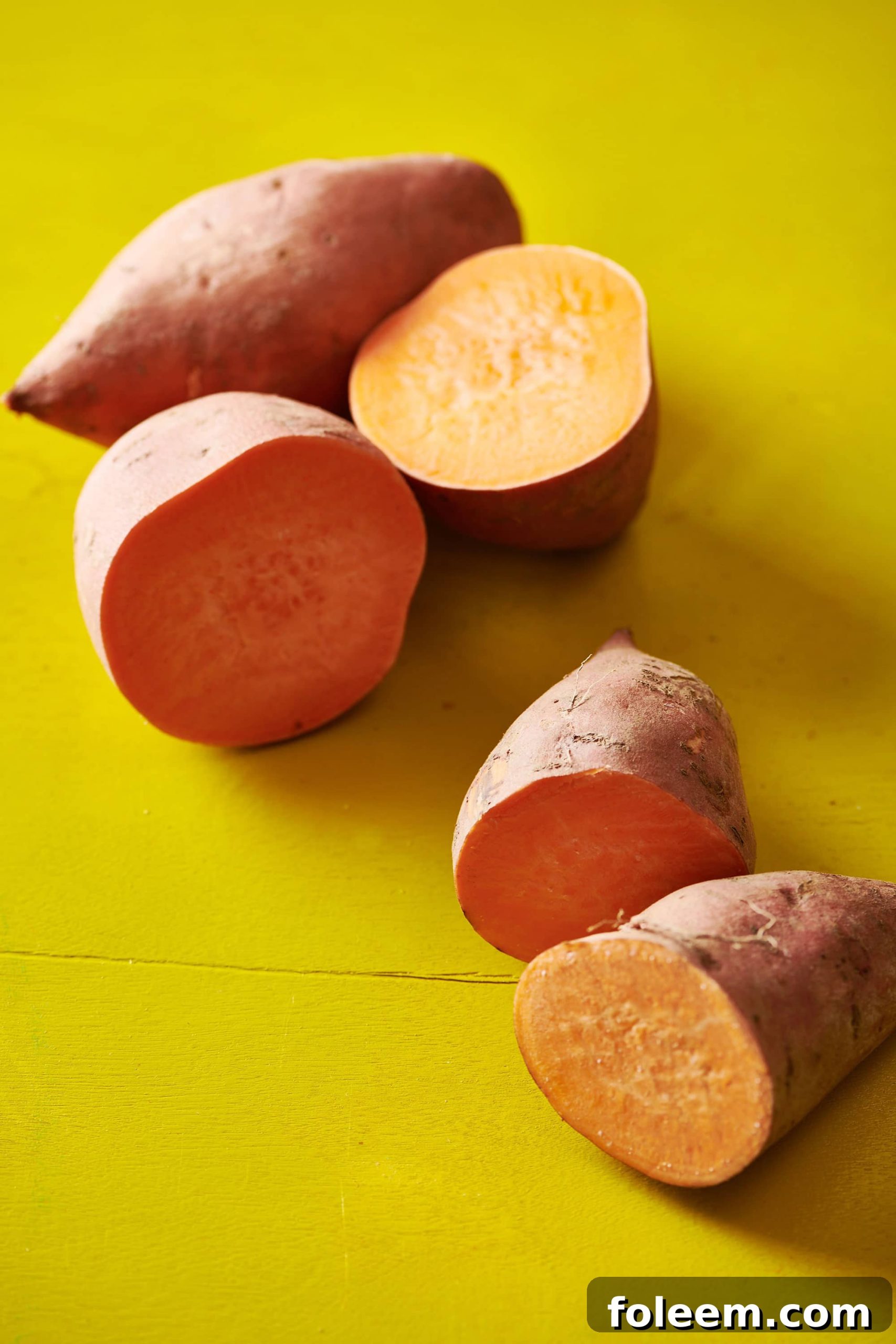 Halved sweet potatoes on a yellow table.