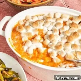 Baking dish of Sweet Potato Casserole with Marshmallows on a pink tablecloth.