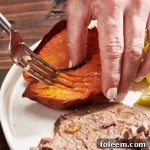 Woman using a fork to mash the inside of a baked sweet potato.