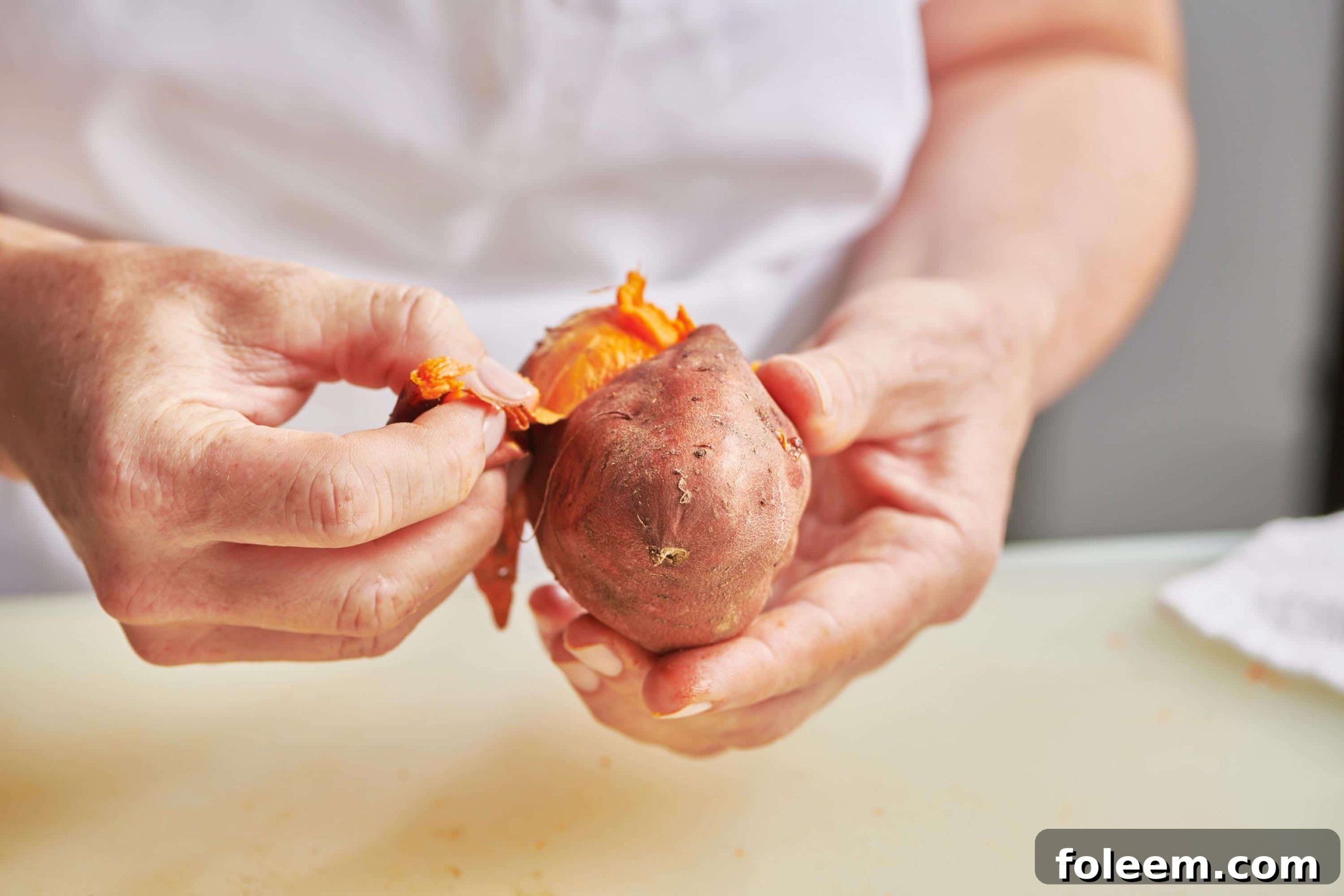 Woman peeling baked sweet potato.