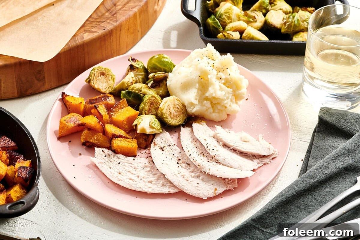 Thanksgiving meal on pink plate with turkey, sweet potatoes, and Brussels sprouts.