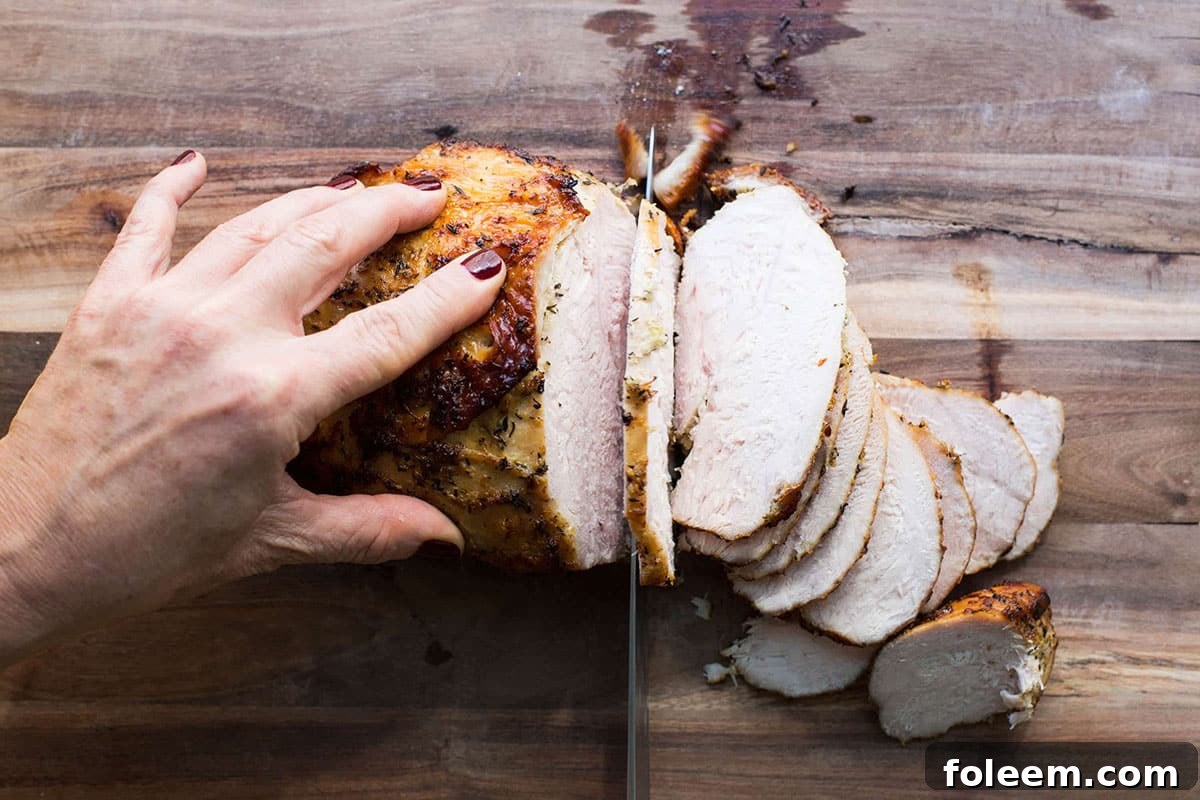 Slicing Lemon-Garlic Roasted Turkey Breast on cutting board.