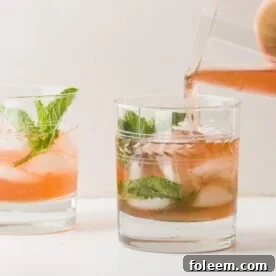 Sparkling Mint Pomegranate Champagne Cocktail being poured into glasses.