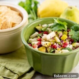 Green bowl of Spicy Pear and Cilantro Salsa and a white bowl of tortilla chips.