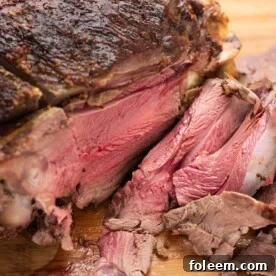 Partially-sliced Lemon-Garlic Semi-Boneless Leg of Lamb on a wooden surface.