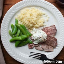 Plate with couscous, peas, and slices of Mediterranean Leg of Lamb with Tzatziki.
