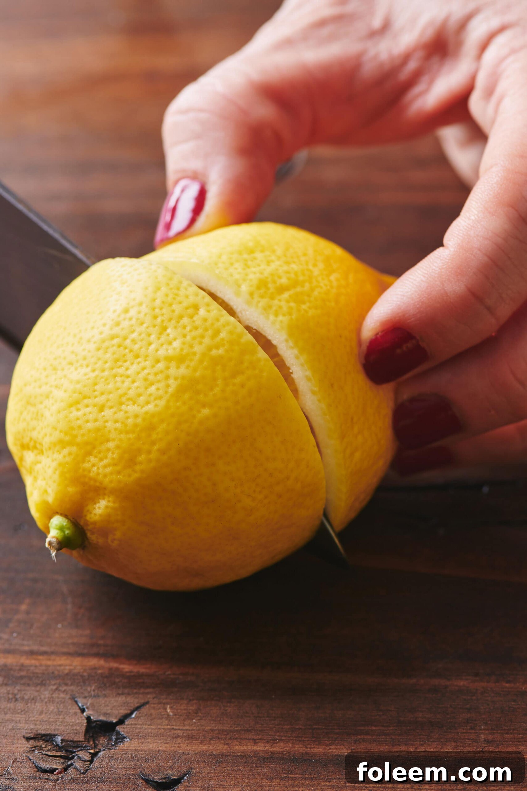 Woman slicing a lemon in half.