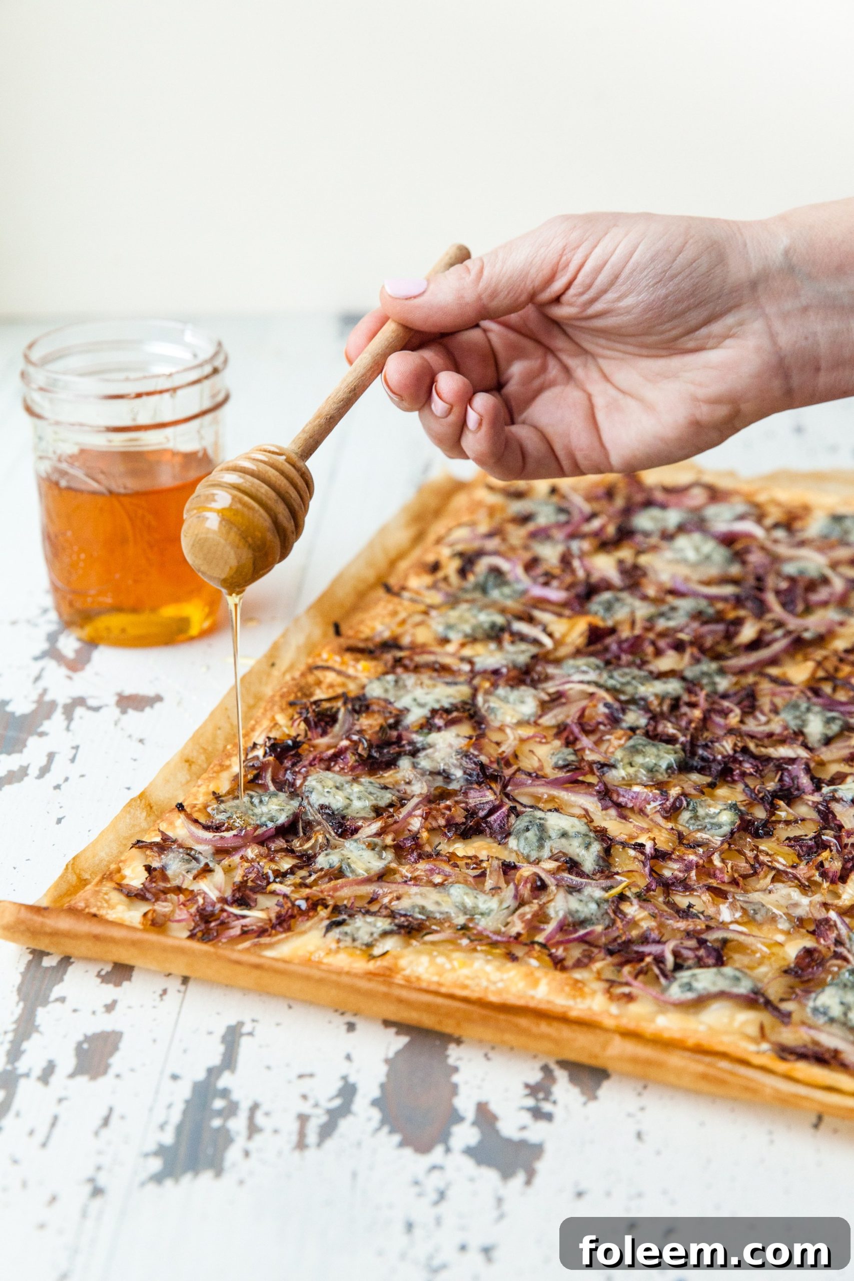 Drizzling honey over flatbread strips with Blue Cheese, Radicchio, and Onion.