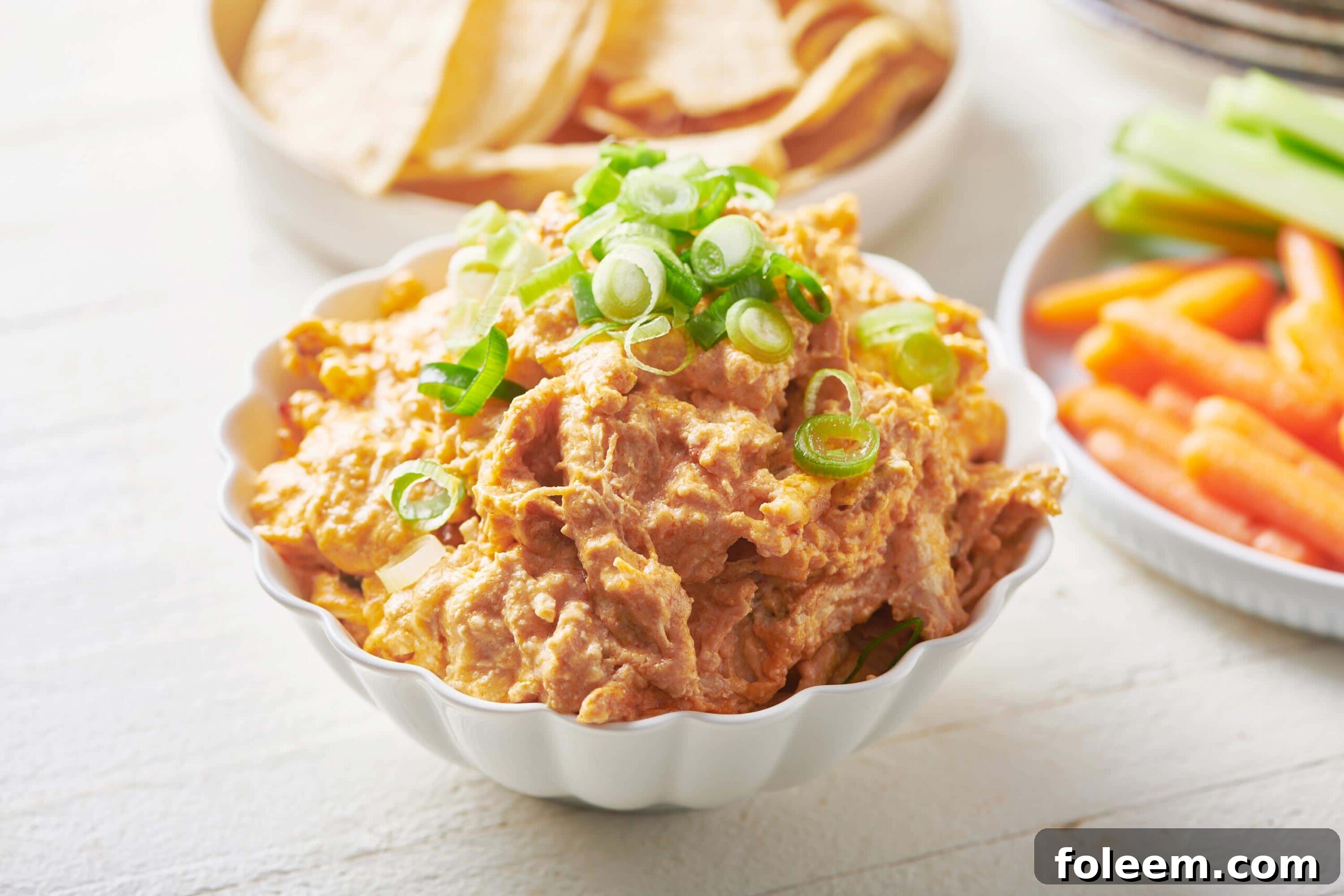 Spoon in a small white bowl of Buffalo Chicken Dip.