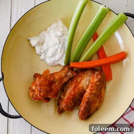 Air-fried Buffalo chicken wings on plate with celery, carrots, and blue cheese dip.