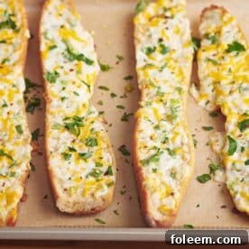 Four slices of cheese garlic bread on parchment-lined baking sheet.