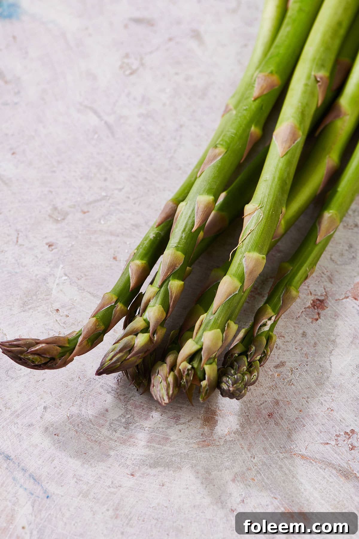 Fresh asparagus spears on white table.